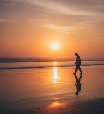 man-walking-beach-sunset-reflection